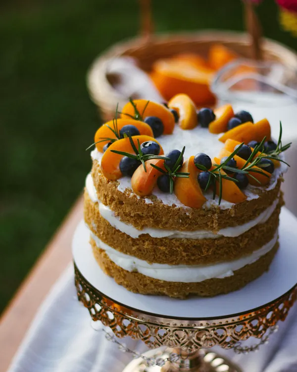 A layer cake with apricots and blueberries on a cake stand (sample photo)